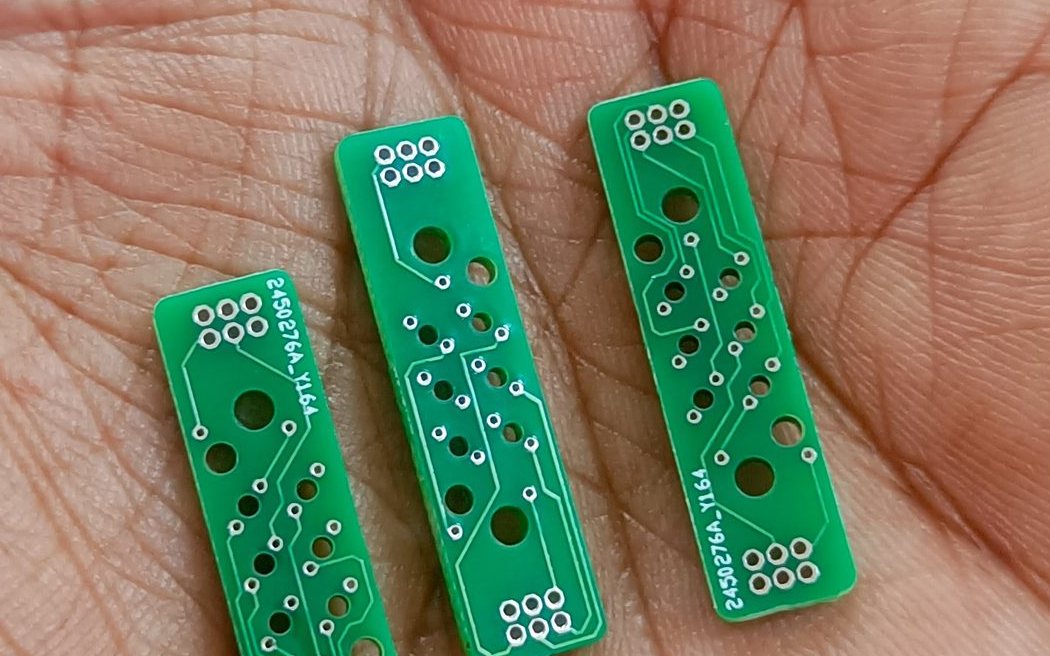 Three Braille cell circuit boards, each about the size of a fingernail, resting in an open palm.