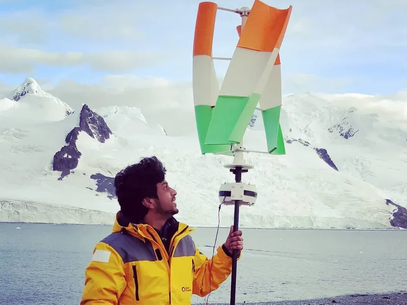 Vijay in a yellow parka beneath the tricolour printed turbine in Antarctica.