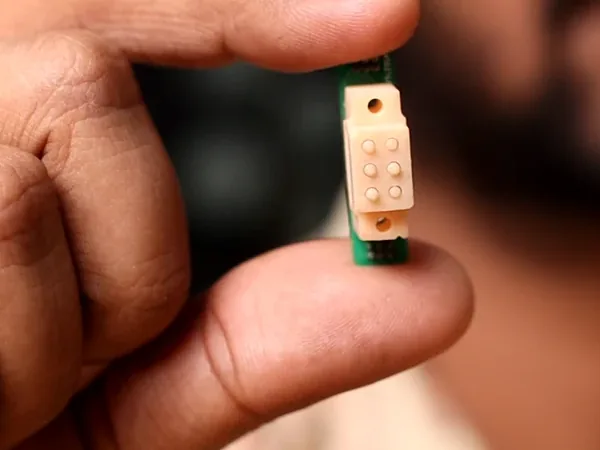 The Braille module held between finger and thumb.