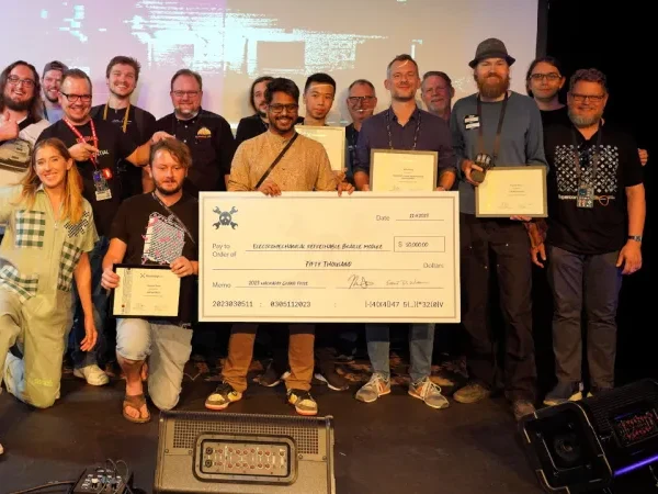 Vijay on the Supercon stage holding the $50,000 Hackaday Prize Grand Prize cheque, the other winners around him.