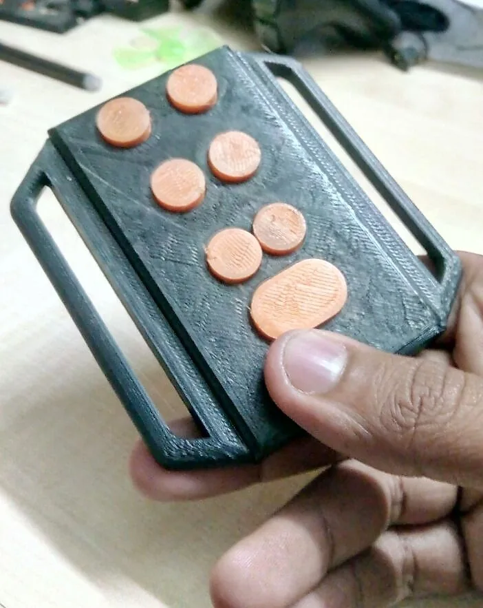 Tipo held in one hand, a thumb resting on its orange Braille keys.